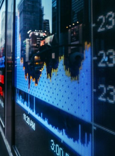 stock charts displayed on a city sidewalk through a glass window