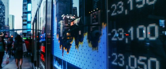 stock charts displayed on a city sidewalk through a glass window